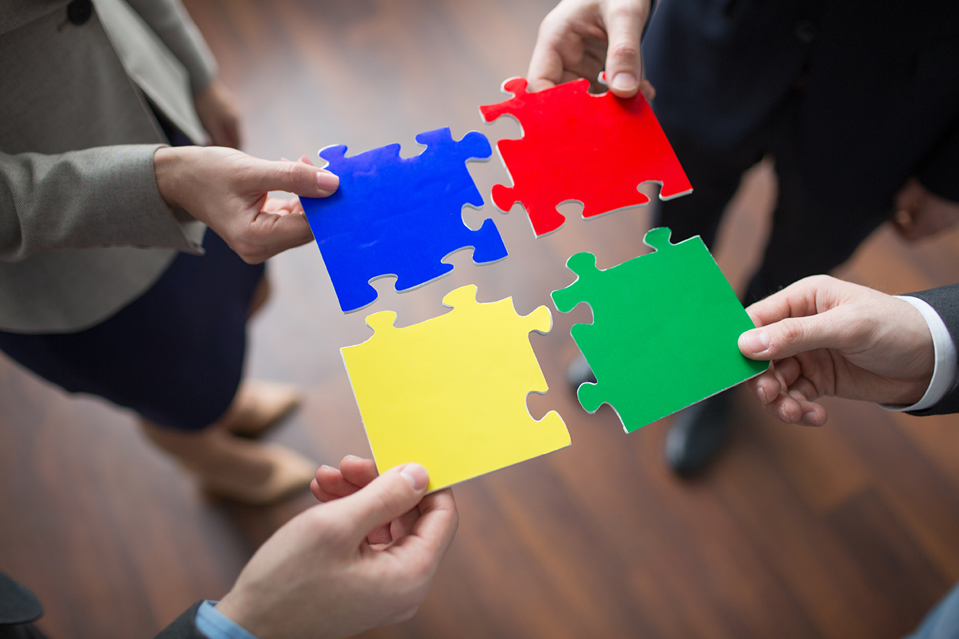 Multi-color puzzle pieces held by co-workers